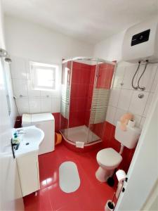 a red and white bathroom with a shower and a toilet at Apartman Nina in Gradac