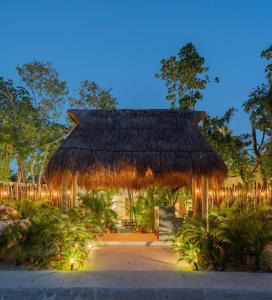 a pavilion with a thatched roof with lights at Suites at TreeTops Tulum in Tulum