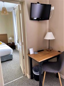 a hotel room with a desk and a tv on the wall at Le Vauban in Merville-Franceville-Plage