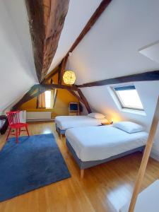 a attic bedroom with two beds and a blue rug at Le Huis Clos in Amboise