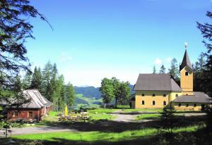 a large building with a church in a field at Hotel Gasthof Seeblick in Zeutschach