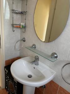 een badkamer met een witte wastafel en een spiegel bij Appartement Limnos Gardens in Paphos City