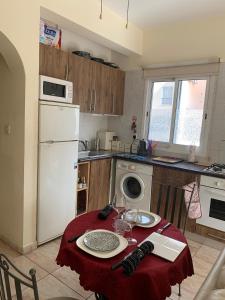 een keuken met een tafel en een witte koelkast bij Appartement Limnos Gardens in Paphos City