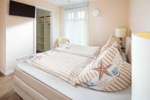 ein Schlafzimmer mit einem Bett mit Kissen und einem Seestern darauf in der Unterkunft Utspann in Norderney