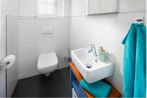 ein weißes Bad mit einem Waschbecken und einem WC in der Unterkunft Utspann in Norderney