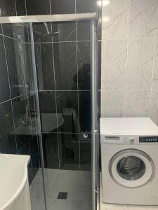 a bathroom with a shower with a washing machine at Kakha's Apartment in Batumi +3 photos