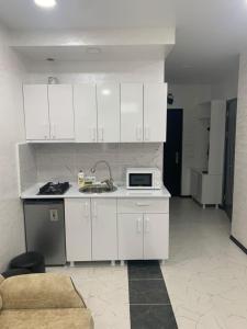 a kitchen with white cabinets and a microwave at Kakha's Apartment in Batumi