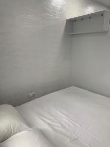 a white bed in a bedroom with a shelf above it at Kakha's Apartment in Batumi