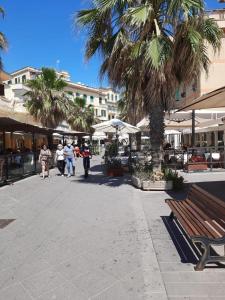a group of people walking down a street with palm trees at Sun&SeaGuestHouse Lido di Roma in Lido di Ostia