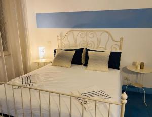 a white bed with a blue headboard and pillows at Sun&SeaGuestHouse Lido di Roma in Lido di Ostia