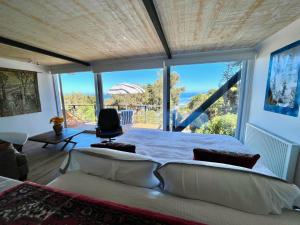 a bedroom with a large bed and a large window at Lofts Casa El Pangue Zapallar in Zapallar