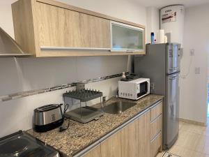 a kitchen with a sink and a microwave and a refrigerator at Departamento Nuevo en Cipolletti in Cipolletti