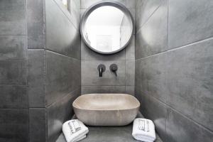 La salle de bains est pourvue d'une grande baignoire et d'un miroir. dans l'établissement Red Beach Harmony suites Modestos, à Akrotiri