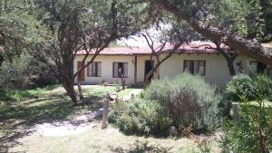uma casa com árvores e arbustos à sua frente em La Haciendita Hostel em Humahuaca