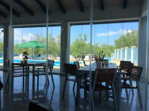 una sala da pranzo con tavolo, sedie e piscina di Pensiunea Pelicanul a Dunavăţu de Jos