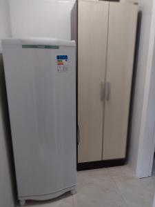 einen weißen Kühlschrank in einem Zimmer neben zwei Schränken in der Unterkunft Kitnet Namorados in Gramado