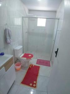 uma casa de banho branca com um chuveiro e um WC. em Kitnet Namorados em Gramado