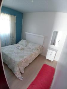 Schlafzimmer mit einem Bett, einem Spiegel und einem roten Teppich in der Unterkunft Kitnet Namorados in Gramado