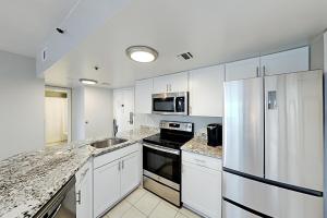 a kitchen with white cabinets and a stainless steel refrigerator at Palace Resort #108 in Myrtle Beach