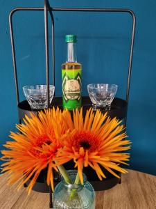 a vase with a bottle and flowers on a table at De Remise in Hengelo