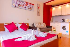 um quarto com uma cama grande e almofadas cor-de-rosa em Green Life Beach Resort Apartment em Sozopol