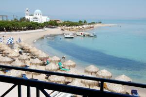 a beach with many straw umbrellas and the ocean at Hotel Alexandra in Skala