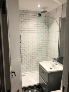 La salle de bains blanche est pourvue d'un lavabo et d'une douche. dans l'établissement 4 The Archways, à Carrick-on-Shannon