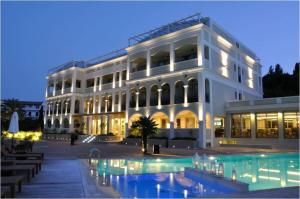 a large white building with a pool in front of it at Corfu Mare Hotel in Corfu