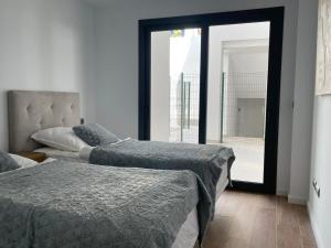 a bedroom with two beds and a large window at Links II 505 Duplex 2bedroom Apartment GOLF Alcaidesa SPAIN in Alcaidesa +11 photos