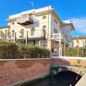 una grande casa bianca con un canale di fronte di Residence Giove a Castelfranco Veneto