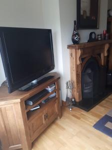 a flat screen tv on a wooden stand with a fireplace at NO 9 The Willows, Ballinamore, Entire home in Ballinamore