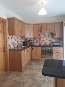 a kitchen with wooden cabinets and a black counter top at NO 9 The Willows, Ballinamore, Entire home in Ballinamore