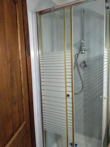 eine Duschkabine mit einer Glastür neben einer Holztür in der Unterkunft Dietro le quinte nel cuore di Perugia in Perugia