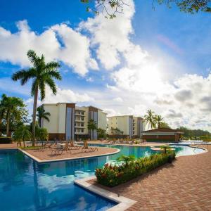 - une piscine avec des palmiers et des bâtiments dans l'établissement Bejuco Beachfront Condo FRENTE A LA PLAYA hermoso condominio NUEVO, à Esterillos Este