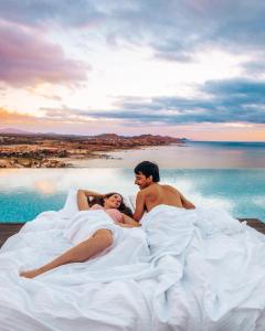 a man and woman laying on a bed in the water at Vista Encantada Resort & Spa Residences, A La Carte All Inclusive Optional in Cabo San Lucas