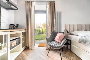 a bedroom with a bed and a chair and a window at Apartamenty MUNN 1 Szczecin in Szczecin