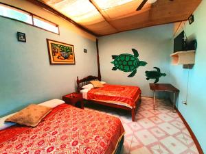 a bedroom with two beds and a turtle on the wall at Alojamiento Sumak Kawsay in Puerto Ayora