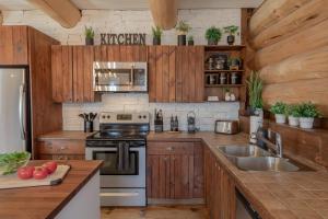 a kitchen with wooden cabinets and stainless steel appliances at Breathtaking log house with HotTub - Winter paradise in Tremblant in Saint-Faustin