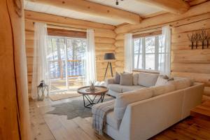 a living room with a couch and a table at Breathtaking log house with HotTub - Summer paradise in Tremblant in Saint-Faustin