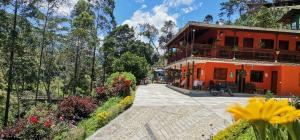 an orange building with a balcony and a garden at Hotel Orillas del Pizano in Jardin