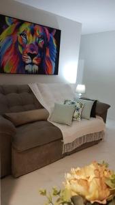 uma sala de estar com um sofá com uma pintura de um leão em Apartamento CONFORTO prox do SHOPPING NAÇÕES prox ABBA Church - cozinha completa - Ar condicionado - WiFi - Smart Tv 32' - Youtube e Apps - estacionamento privado - Portaria 24h - Acomoda até 8 pessoas - Anfitriã SuperHost no BNB 5 Estrelas em Criciúma