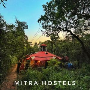 a house with a red roof in a forest at Mitra Hostel Vagator in Vagator