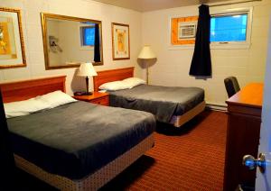 a hotel room with two beds and a mirror at Chalet Inn Motel in Dryden