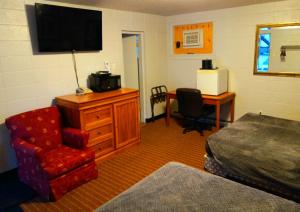 a hotel room with a bed and a television and a chair at Chalet Inn Motel in Dryden +8 photos