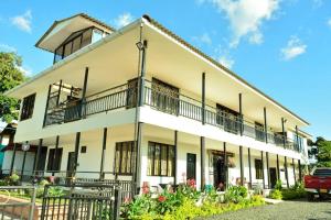 - un grand bâtiment blanc avec des balcons et des fleurs dans l'établissement Finca Hotel el Guadual, à Quimbaya