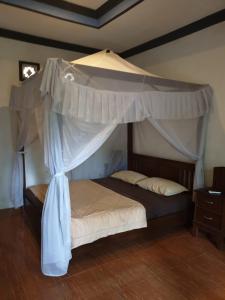 a bedroom with a canopy bed with a wooden floor at Five Time Home Stay in Gili Air