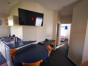 a kitchen with a table, chairs and a microwave at Airport Birches Motel in Christchurch