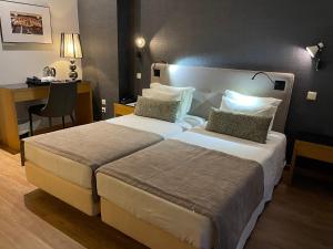 a hotel room with a bed and two lamps at Hotel Sete Colinas in Lisbon