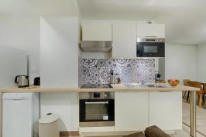 a kitchen with white cabinets and a stove top oven at Superbe T3 proche Vieux-Port in Marseille