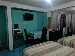 a hotel room with a desk and a room with two beds at Hospedaje La Cienega in Zacatlán